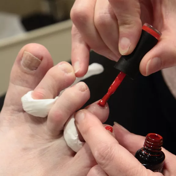 close-up foto van teennagels die rood gelakt worden 