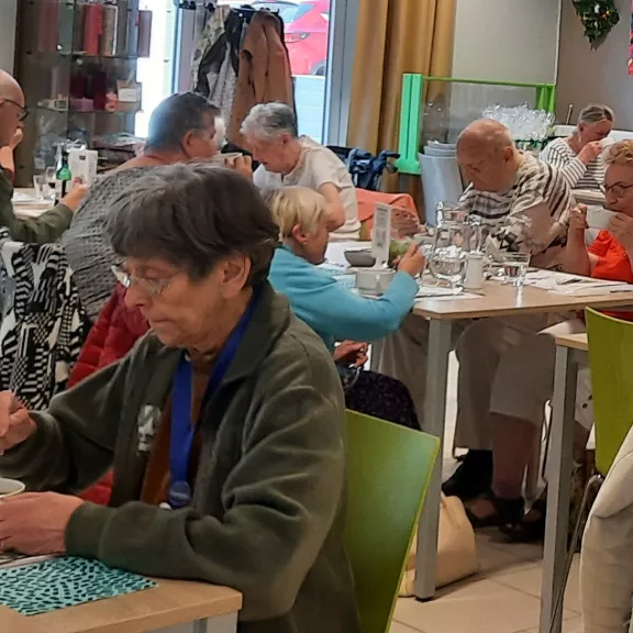 Mensen genieten van een maaltijd in een sociaal restaurant, met tafels gezellig ingericht en een ontspannen sfeer onder de aanwezigen.