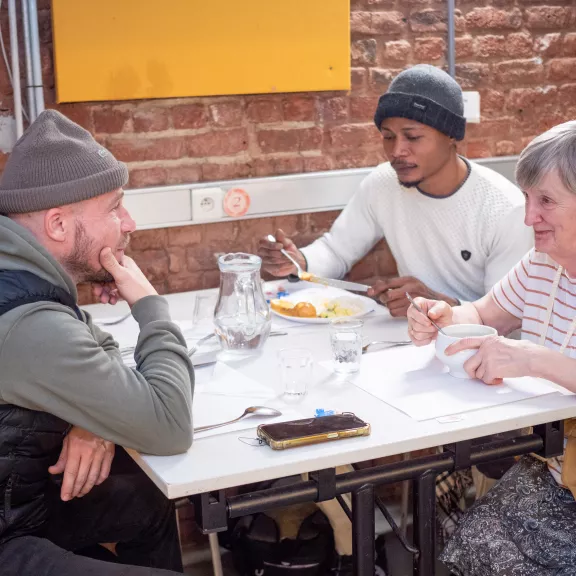 Drie mensen samen aan tafel aan het eten en praten