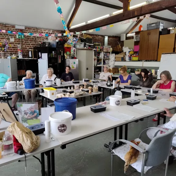Mensen die samen zitten aan tafel die in een U-vorm staat en luisteren naar een uitleg