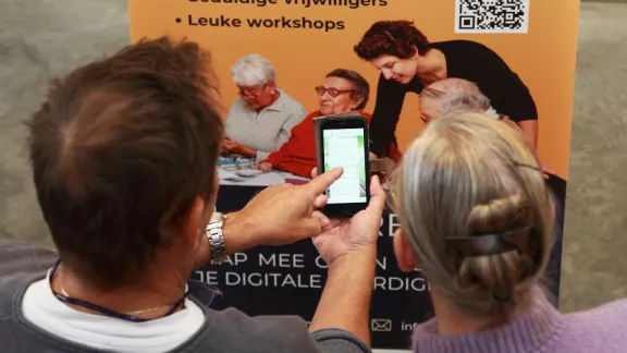 Een persoon legt iets uit aan de ander terwijl ze samen naar een smartphone kijken.