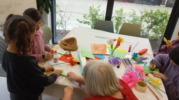 mensen rond een tafel vol creatief materiaal
